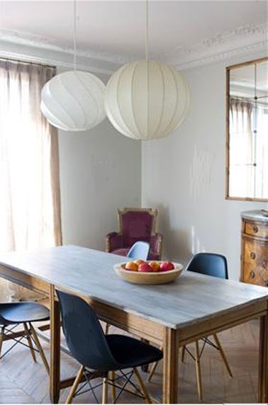 Mélange de style réussi dans cette salle où les touches de couleurs multiples s'harmonisent autour des deux nuances de gris clair de la peinture murale. Fauteuils ancien tapissé d'un velours lie de vin, plateau de la table en bleu clair, chaise bleu/noir