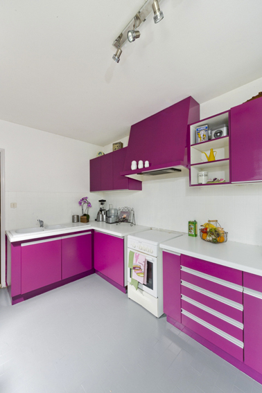 Pour repeindre un meuble de cuisine avec la peinture pour meuble GripActiv V33 dans cette cuisine sans poncer deux couches de peinture couleur violet sur les façades des meubles haut et bas et couleur blanc sur la crédence en carrelage. Photo après