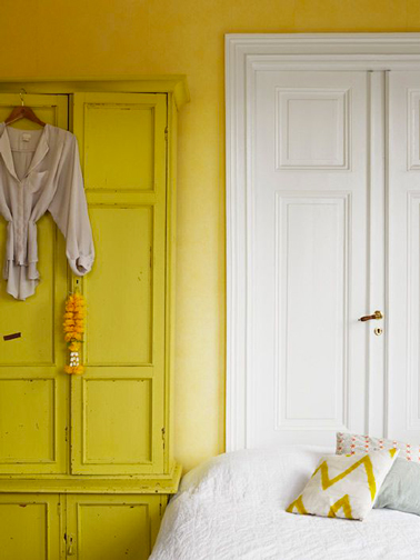 2 couleurs de jaune pour la peinture d'une chambre : Sur les murs une peinture jaune orangé contraste avec le blanc des boiseries, tandis que l'armoire ancienne est peinte avec un jaune citron lumineux