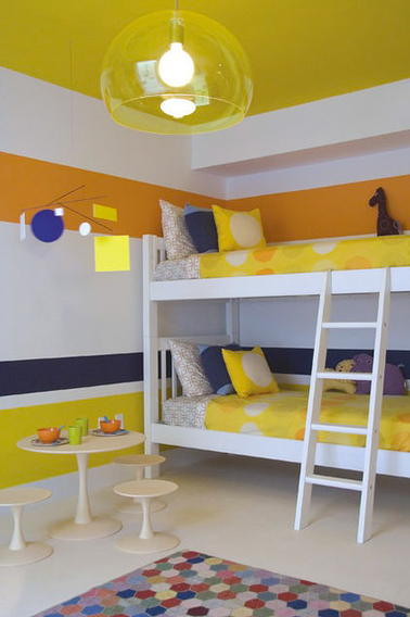 Déco d'une chambre partagée par 2 enfants avec des bandes de peinture jaune acidulé, orange et bleu marine sur une base de peinture blanche.