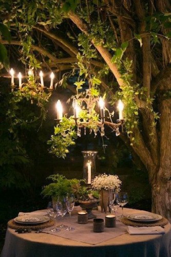 Quoi de plus romantique pour un dîner en tête à tête dans le jardin que de suspendre 2 lustres dans un arbre et d'avoir un photophore sur la table ronde !