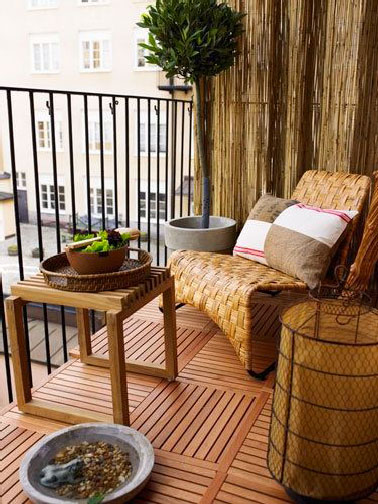 Une ambiance chaleureuse se dégage sur ce balcon aménagé tout en bois. Dalles, canisse et mobilier en rotin dans la même tonalité de blond doré.